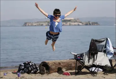  ?? JANE TYSKA — STAFF PHOTOGRAPH­ER ?? Pierce Jackson, 11, of Vacaville, jumps off a log during an outing with his family Thursday at the beach at Crissy Field in San Francisco. The family had originally planned a ski trip to Lake Tahoe, but changed plans because of concerns about the snow conditions.