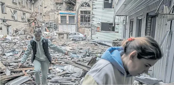  ?? THE NEW YORK TIMES ?? Destrucció­n. Dos habitantes de Járkov, la segunda ciudad de Ucrania, caminan entre los destrozos de un edificio.