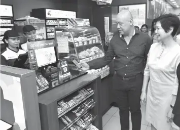  ??  ?? Globe President and CEO Ernest Cu demonstrat­es to Robinsons Retail Holdings President and COO Robina Gokongwei- Pe how GCash QR works.