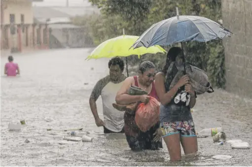  ?? DELMER MARTINEZ/ AP ?? Residents wade through a flooded road carrying belongings in Progreso Yoro, Honduras, on Wednesday.