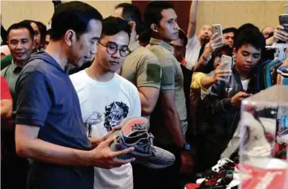  ?? [FOTO AGENSI] ?? Jokowi dan anak lelakinya, Gibran Rakabuming Raka (dua dari kiri) ketika mengunjung­i pameran Hari Sniker Jakarta di pusat beli-belah Senayan City, di Jakarta Tengah.