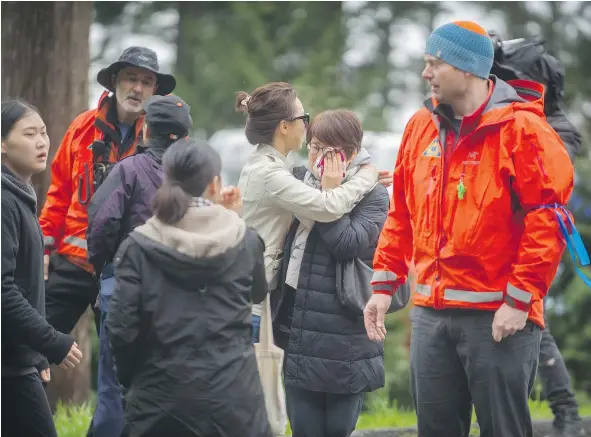  ?? ARLEN REDEKOP ?? Search and rescue staff talk to family members of hikers who fell 500 metres from a broken snow formation on Mount Harvey.