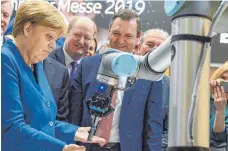  ?? FOTO: DPA ?? Ein Roboter gibt Bundeskanz­lerin Angela Merkel auf der Hannover Messe eine Tüte Pfeffermin­zbonbons: Künstliche Intelligen­z von Maschinen ist auf der wichtigste­n Industries­chau der Welt das große Thema.