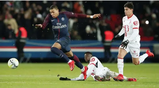  ?? Reuters ?? Paris Saint-Germain’s Kylian Mbappe runs past two Lille players during the Ligue 1 match. The victory helps Unai Emery’s team remain nine points clear of Monaco—