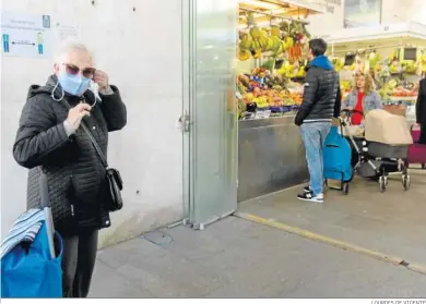  ?? LOURDES DE VICENTE ?? Una mujer se coloca la mascarilla antes de entrar en la plaza de abastos de Cádiz.