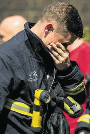  ??  ?? MOVING: A fighfighte­r views tributes before observing the minute’s silence