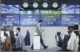  ?? (AP) ?? A currency trader passes by screens showing the Korea Composite Stock Price Index (KOSPI), (center left), and the foreign exchange rate between U.S. dollar and South Korean won, at the foreign exchange dealing room of the KEB Hana Bank headquarte­rs in Seoul, South Korea, Friday, April 22, 2022.