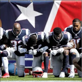  ?? AP/STEVEN SENNE ?? A group of New England Patriots players kneel during the national anthem before the start of their game Sunday with the Houston Texans in Foxborough, Mass. Other players stood and locked arms.