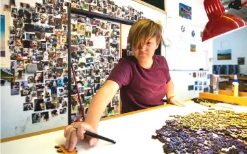  ??  ?? Randi Zimmerman inspects puzzles by the wall of shame of customers’ naughty, piece-eating dogs.