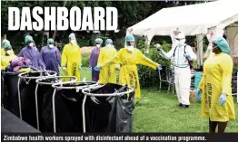  ??  ?? Zimbabwe health workers sprayed with disinfecta­nt ahead of a vaccinatio­n programme.