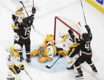  ?? Associated Press ?? Nashville goalie Juuse Saros looks up from the ice as Arizona’s Brad Richardson (15) and Michael Grabner (40) celebrate the winning goal in overtime.