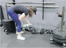  ?? JEFF CHIU, THE ASSOCIATED PRESS ?? Alexis Garrod, CrossFit Potrero Hill partner and head coach, cleans off weight-training equipment in an empty San Francisco gym.