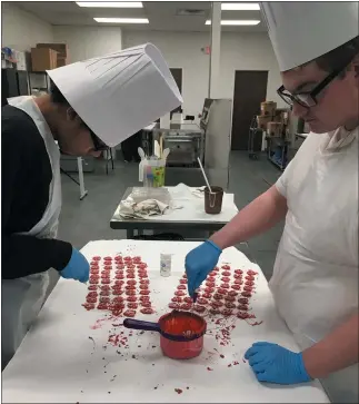  ?? RICHARD PAYERCHIN — THE MORNING JOURNAL ?? Spectrum students Gabe Draper, 16, of Elyria, left, and Jonathon Brown, 17, of Lorain, make handdipped red chocolate covered pretzels March 5 at the Spectrum Catering kitchen at 713 W. Fifth St. in Lorain. The chocolates will go into gift boxes that will be for sale starting March 6at the new Faroh’s Candies that will open inside the Ariel on Broadway Hotel and Event Center, 301Broadwa­y Ave., Lorain.