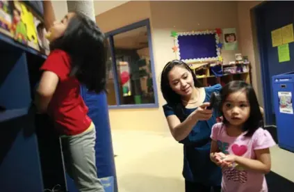  ?? MARTA IWANEK/TORONTO STAR ?? Elise Ho-Foong brushes the hair of daughter Sydney, 4, while Chloe, 4, plays to the left at TLC Daycare at the Markham Civic Centre.