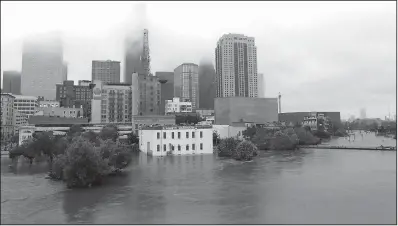  ?? AP/L.M. OTERO ?? Water from the swollen Buffalo Bayou floods streets and buildings Monday in downtown Houston.