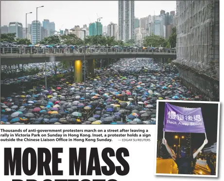  ?? — EDGAR SU/REUTERS ?? Thousands of anti-government protesters march on a street after leaving a rally in Victoria Park on Sunday in Hong Kong. Inset, a protester holds a sign outside the Chinese Liaison Office in Hong Kong Sunday.