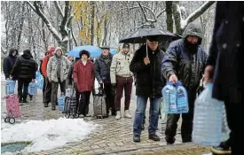  ?? /Reuters ?? Power and water disruption­s: Residents stand in line to fill up bottles with fresh drinking water after critical infrastruc­ture in Kyiv was hit by Russian missile attacks.