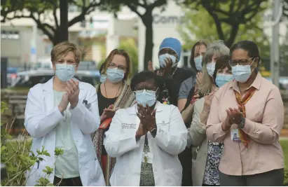  ?? MICHAEL MCANDREWS PHOTOS/SPECIAL TO THE COURANT ?? A group of Saint Francis Hospital staff applauds a speaker during an event outside the hospital Friday that remembered more than 3,000 COVID-19 patients treated at the hospital during the pandemic.