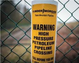  ?? CP FILE PHOTO ?? A sign warning of an undergroun­d petroleum pipeline is seen on a fence at Kinder Morgan’s facility in Burnby, the terminal of the Trans Mountain Pipeline.