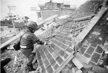  ??  ?? A rescue worker marks debris in the city of Juchitan, after an earthquake struck the southern coast of Mexico late on Thursday, in Mexico. — Reuters photo