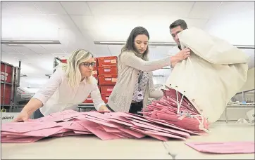  ?? THE ASSOCIATED PRESS ?? Election workers Heidi McGettigan, from left, Margaret Wohlford and David Jensen unload a bag of ballots in June brought in a from a polling precinct to the Sacramento County Registrar of Voters office.