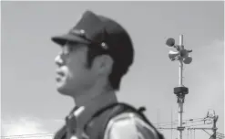  ?? SHIHO FUKADA/FOR THE WASHINGTON POST ?? A police officer from Sakata City Police Department stands in front of siren installed to warn of a North Korea missile attack at Nishiarase community center during a missile drill in Sakata city, Yamagata Prefecture, Japan, on June 9, 2017.