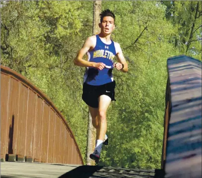  ?? PHOTOS BY BRIAN SUMPTER ?? Isaac Rascon of Middletown High School crosses the bridge that leads to the finish line Wednesday at Clear Lake State Park. He had a big lead over his closest pursuer and won the 3.1-mile boys race in 17 minutes, 43 seconds, capping his undefeated senior season.