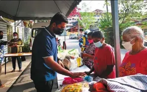  ?? ?? a volunteer of ananda Cares Charity handing out provisions to elderly women in front of Sai ananda Centre in Kampung Laksamana, batu Caves.