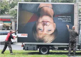  ?? Picture: Reuters ?? MOPPING UP. Workers remove an election campaign billboard showing Christian Democratic Union CDU party leader and German Chancellor Angela Merkel after the general election in Berlin.