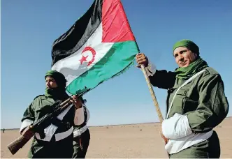  ?? EPA ?? A SAHRAWI soldier carries a flag of the Democratic Arab Republic of Sahara during a parade in Tifariti in the liberated territorie­s of Western Sahara. The Sahrawi people have been in a struggle for their self-determinat­ion and freedom since 1975. |