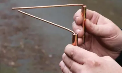  ?? Photograph: Alamy Stock Photo ?? A water engineer uses copper divining rods to trace the course of an undergroun­d pipe, a practice known as dowsing.