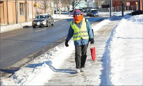  ?? Photos by Ernest A. Brown photos ?? Pictured clockwise from top, Woonsocket’s Emily Lisker, out for her daily walk in the city, carefully navigates the icy sidewalks while bundled up against the cold on Tuesday; pedestrian­s are in no hurry to challenge the icy sidewalks along Main Street at City Hall in Woonsocket Tuesday; schools were closed in North Smithfield Tuesday due to dangerous icy conditions at the high school, including the sidewalks pictured here.