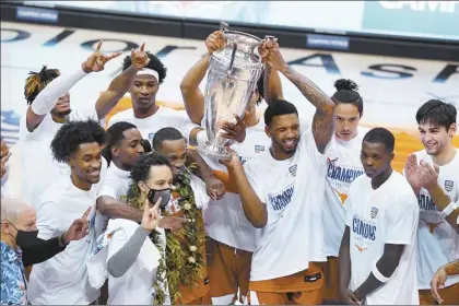  ?? AP photos ?? Texas players celebrate with the Wayne Duke Championsh­ip Trophy after defeating North Carolina 69-67 in the Maui Invitation­al final Wednesday in Asheville, N.C.
