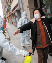  ??  ?? A woman who has recovered from the COVID-19 coronaviru­s infection, is disinfecte­d by volunteers as she arrives at a hotel for a 14-day quarantine after being discharged from a hospital in Wuhan, in China’s central Hubei province