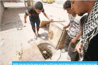  ?? — AFP ?? BASRA: Iraqi men show the sewer pit on June 9, 2018 where Imed Al-Rubaye and Adel Al-Sari died trying to save a 7-year-old child who had fallen into it.