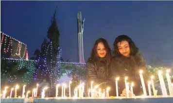  ?? — Reuters ?? Two women light candles outside a church on the Christmas eve in Chandigarh, on Sunday.