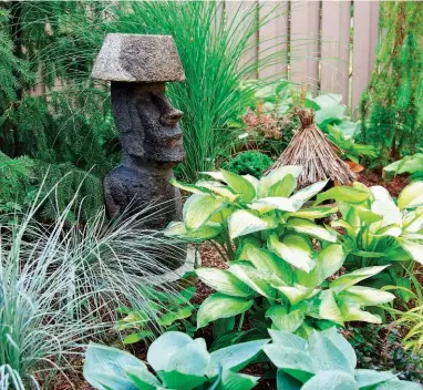  ??  ?? ABOVE: Carefully placed accents, including a replica of an Easter Island statue, give the property’s greenery and flowers added inerest. ABOVE RIGHT: Reed grass harmonizes with barberry shrub. RIGHT: Fran Brown works on a section of her backyard.