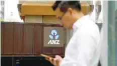  ?? — Reuters ?? A man uses his mobile phone in front of an ANZ bank branch in Sydney.