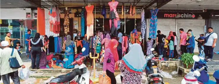  ?? FOTO: NIK ABDULLAH NIK OMAR ?? ORANG ramai membeli pakaian di beberapa kedai kain yang membuat jualan lelong di pekan Rantau Panjang selepas kedai mereka dilanda banjir.
