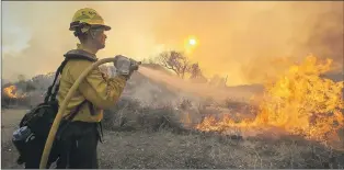  ?? AP PHOTO ?? A firefighte­r battles a wildfire near Placenta Canyon Road in Santa Clarita, Calif., Sunday. Thousands of homes remained evacuated Sunday as two massive wildfires raged in tinder-dry California hills and canyons.