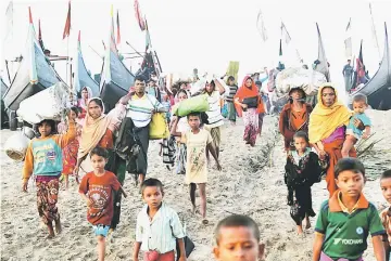  ??  ?? A group of Rohingya refugees, who fled from Myanmar by boat Wednesday night, walks towards a makeshift camp in Cox’s Bazar, Bangladesh. —Reuters photo