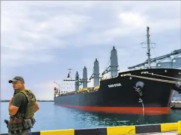  ?? A SECURITY OFFICER David Goldman Associated Press ?? in Odesa, Ukraine, stands Friday next to the ship Navi-Star, which has sat full of grain since the Russian invasion of Ukraine five months ago. Commercial port traffic is Odesa’s lifeblood.
