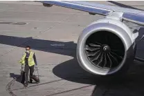  ?? Joe Raedle / Getty Images ?? A ground crew member helps push American Airlines Flight 718 away from its gate at Miami Internatio­nal Airport on Tuesday in its first flight to New York.