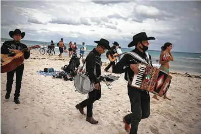  ?? Photos by Emilio Espejel / Associated Press ?? Roving musicians look for tourists to serenade on Mamitas beach in Playa del Carmen, Mexico. Tens of thousands of American tourists descended on Mexico’s glittering Caribbean beaches at the close of 2020 and start of this year.