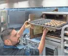  ?? ?? Chef Nick Guevara takes muffins out of the oven at The Lord’s Place new client service center in West Palm Beach Thursday. The center opened and began serving clients in early June.