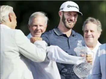  ?? THE ASSOCIATED PRESS ?? Dustin Johnson, second from right, is presented with his trophy and winner’s jacket after winning the St. Jude Classic golf tournament Sunday.