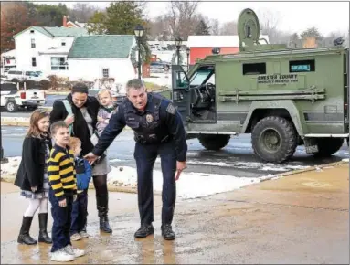  ?? TOM KELLY III – DIGITAL FIRST MEDIA ?? West Pottsgrove Township Police Chief Matt Stofflet greets the Walsh family as they arrive for a Christmas event held for 4-year-old Kieran, who is battling cancer. The Walsh family, from left, Maya, Seamus, Kieran (who is already looking at the SWAT...