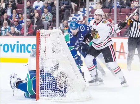  ??  ?? Canucks goalie Jacob Markstrom winds up in his net and Vancouver defenceman Erik Gudbranson, centre, looks on helplessly Wednesday night as the Blackhawks’ Brandon Saad celebrates his first-period goal at Rogers Arena.