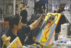  ??  ?? Above: Artist John Thomason paints behind the counter while selling some of his prints in Artist Alley at Grape City Con on Sunday. Right: Ron Mullins of Sacramento wields a lightsaber as Luke Skywalker from “Star Wars: The Force Awakens” during the...