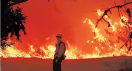  ?? MARCIO JOSE SANCHEZ/AP ?? A member of the Los Angeles County Fire Department stands in front of the advancing Bobcat Fire while protecting a home last week in Juniper Hills, California.